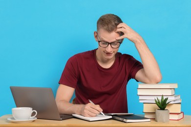 Photo of Student preparing for exam at table against light blue background