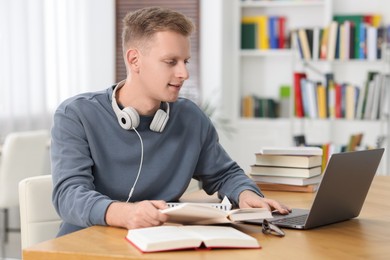 Student preparing for exam with laptop at table indoors