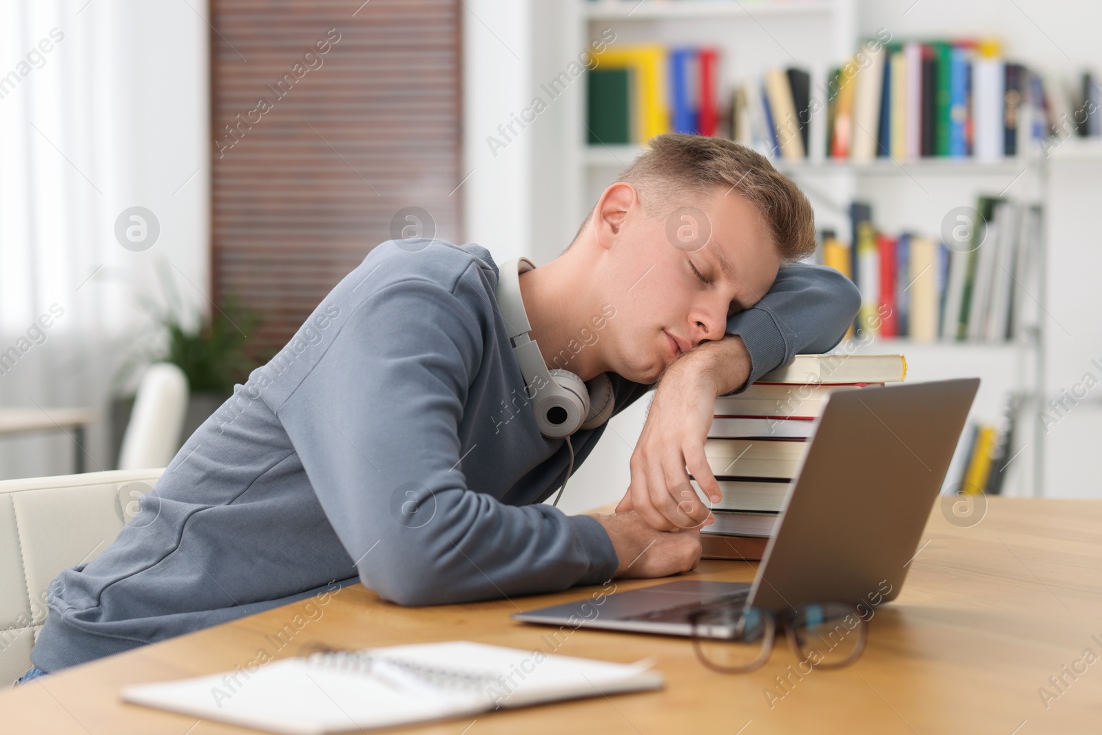 Photo of Preparing for exam. Tired student sleeping among books at table indoors