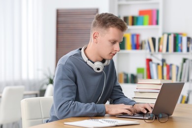 Photo of Student preparing for exam with laptop at table indoors