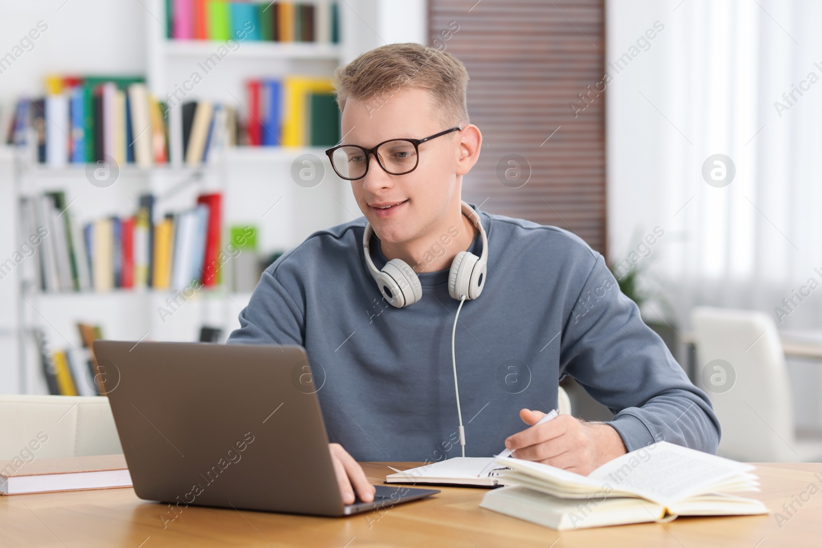 Photo of Student preparing for exam with laptop at table indoors