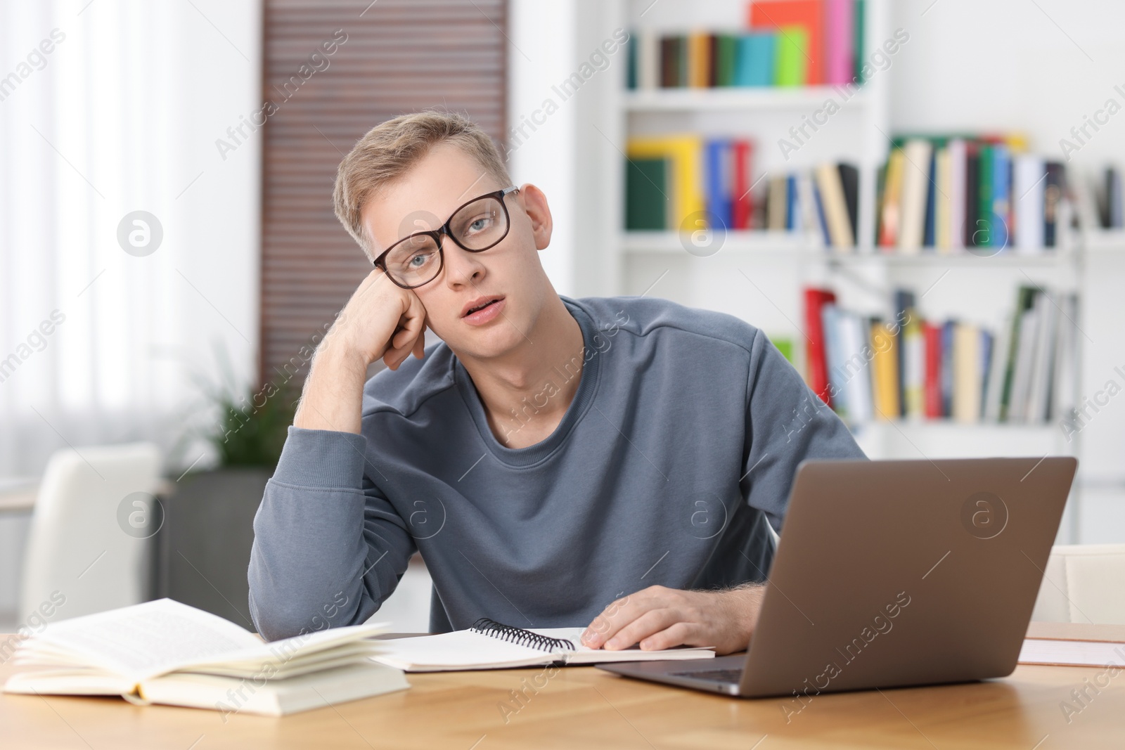 Photo of Preparing for exam. Student with laptop and book at table indoors