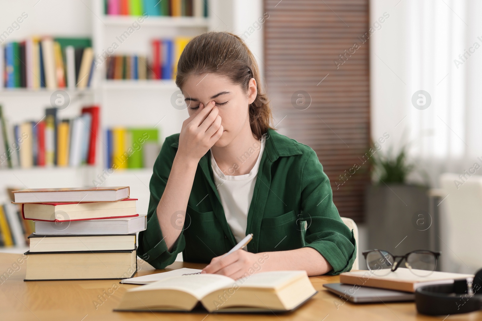 Photo of Tired student preparing for exam at table indoors