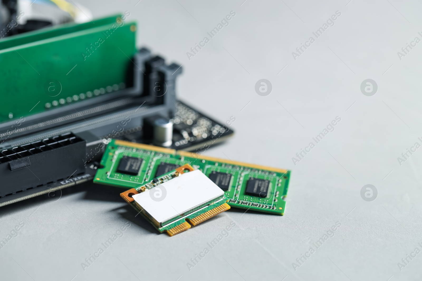 Photo of Wi-Fi card, RAM chip and computer motherboard on grey table, closeup