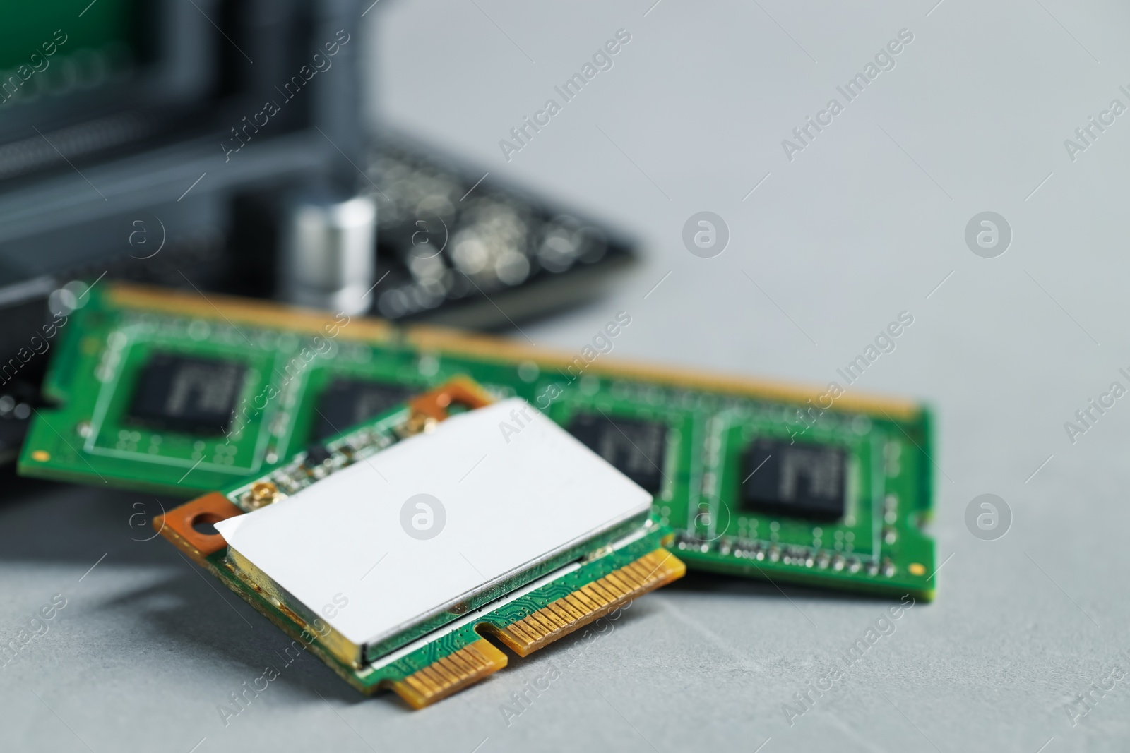 Photo of Wi-Fi card, RAM chip and computer motherboard on grey table, closeup