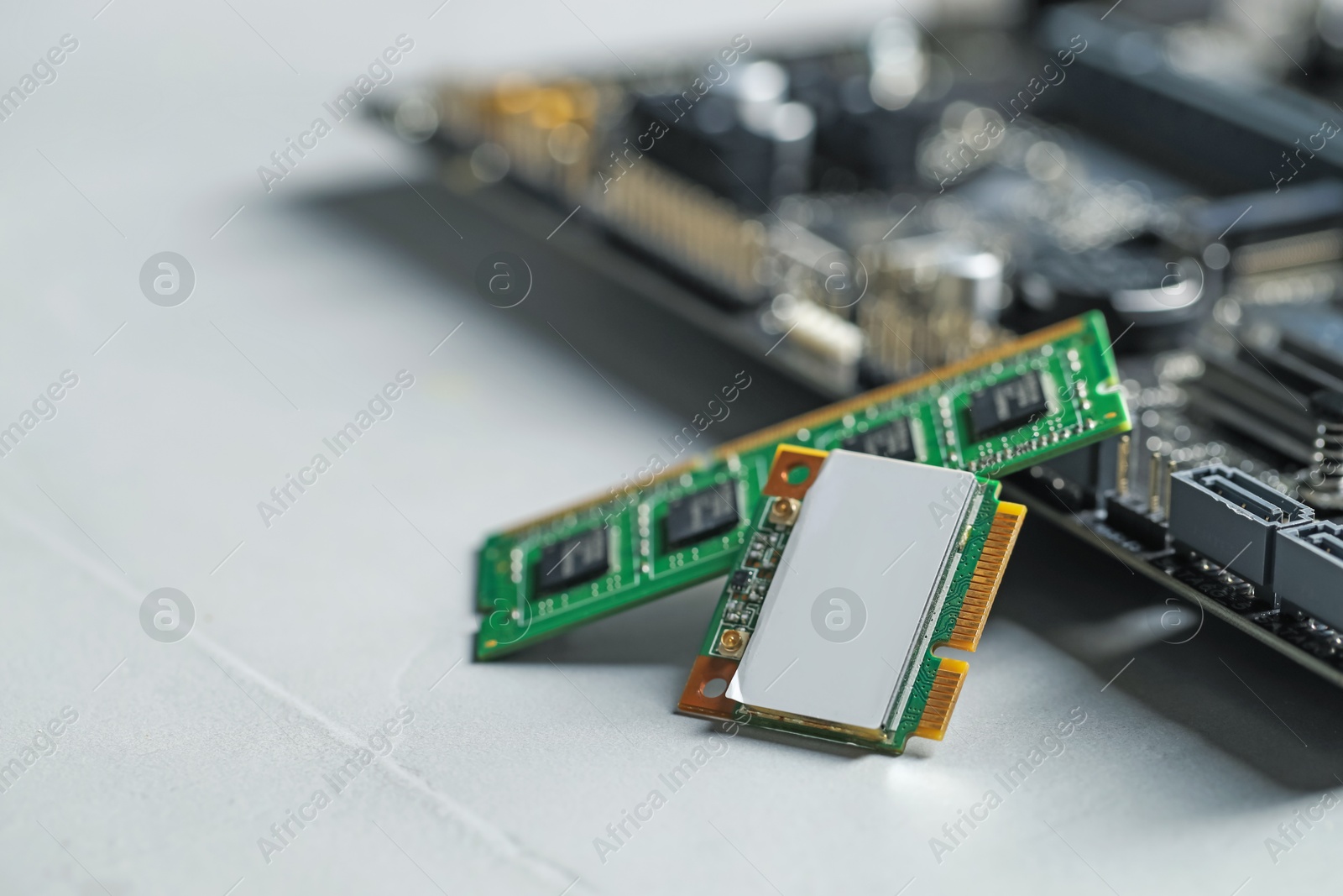 Photo of Wi-Fi card, RAM chip and computer motherboard on grey table, closeup