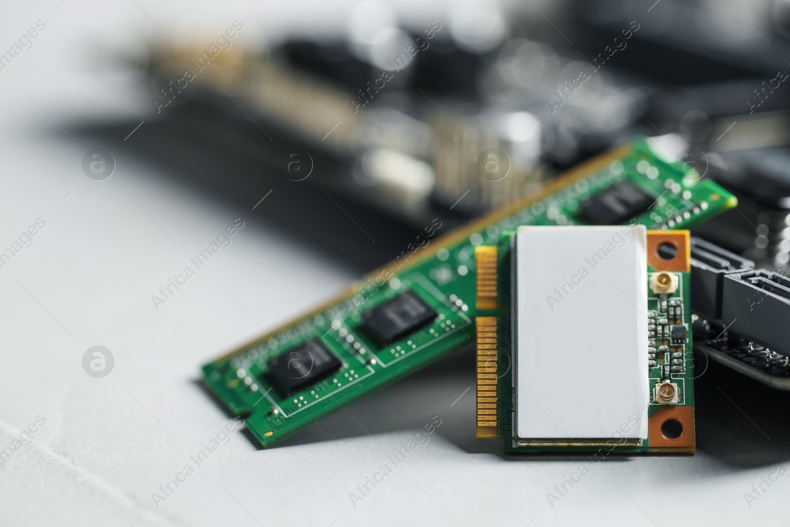 Photo of Wi-Fi card, RAM chip and computer motherboard on grey table, closeup