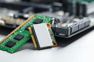 Photo of Wi-Fi card, RAM chip and computer motherboard on grey table, closeup