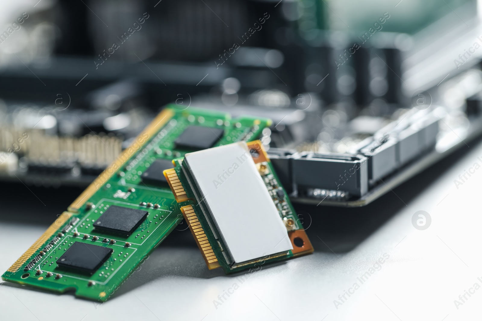 Photo of Wi-Fi card, RAM chip and computer motherboard on grey table, closeup