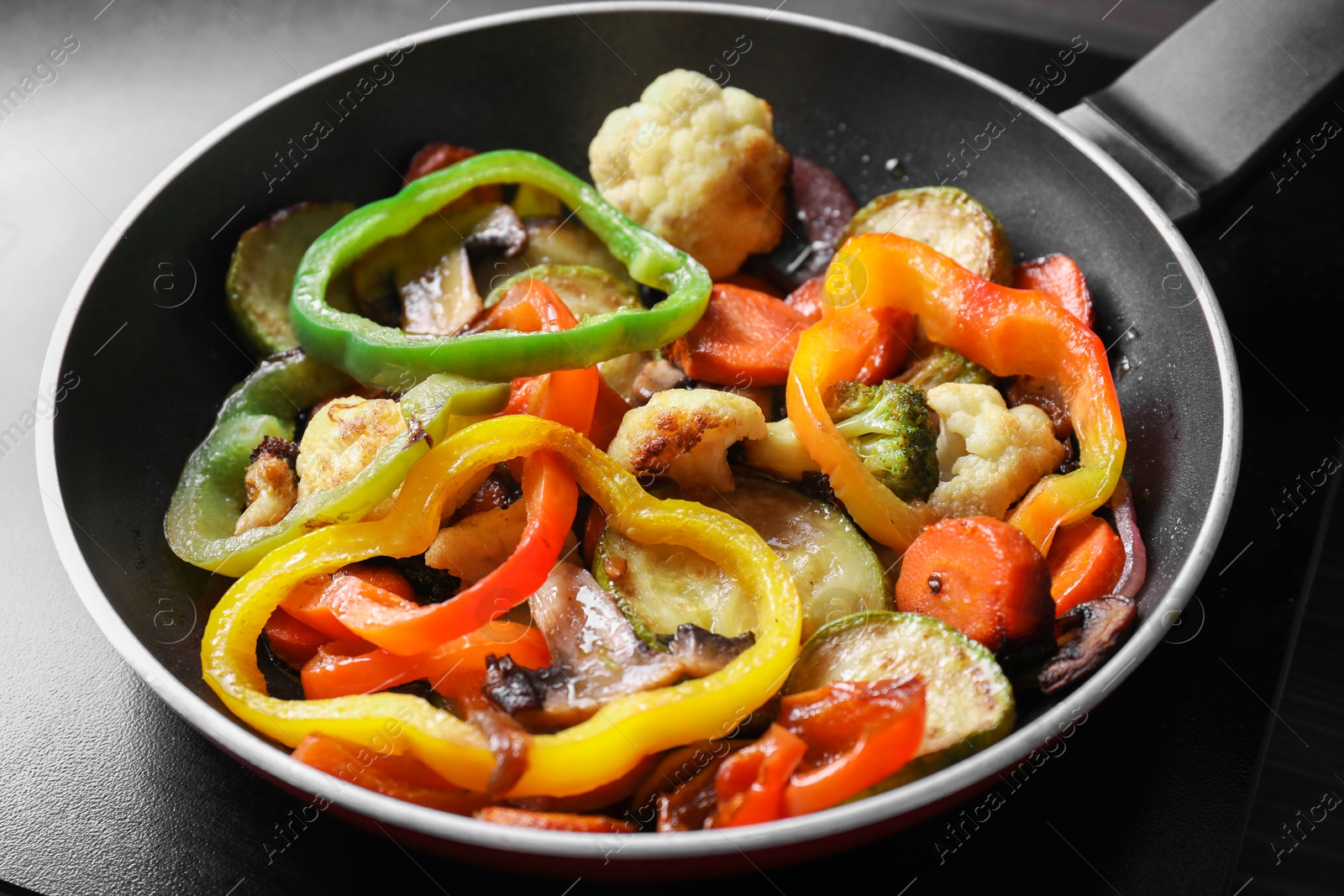 Photo of Frying pan with vegetables and mushrooms on stove, closeup