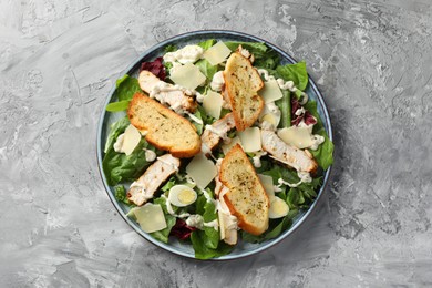 Tasty Caesar salad with chicken on gray textured table, top view