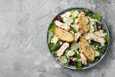 Photo of Tasty Caesar salad with chicken on gray textured table, top view. Space for text