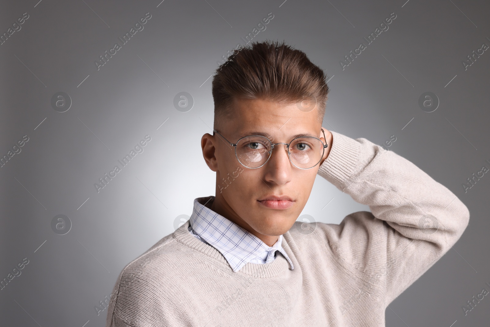 Photo of Handsome young man with stylish haircut on grey background