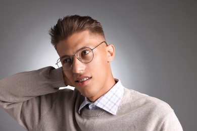 Photo of Handsome young man with stylish haircut on grey background