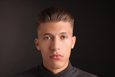 Photo of Handsome young man with stylish haircut on black background