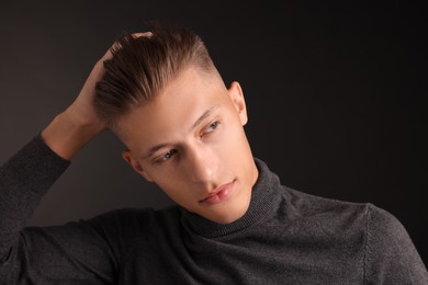 Photo of Confident young man with stylish haircut on black background