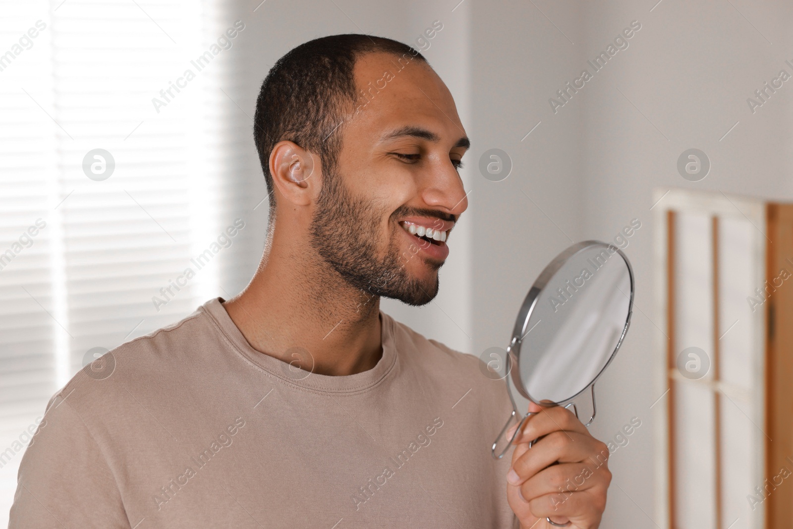 Photo of Smiling man looking at mirror in room