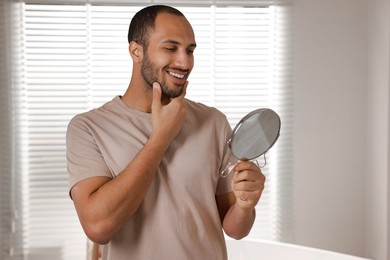 Photo of Smiling man looking at mirror in room