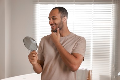 Photo of Smiling man looking at mirror in room