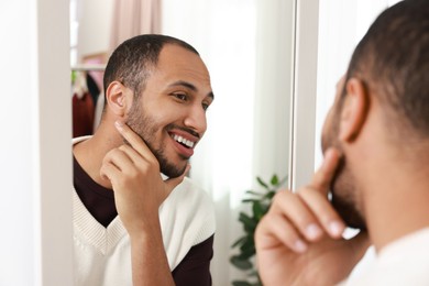 Photo of Smiling man looking at mirror at home