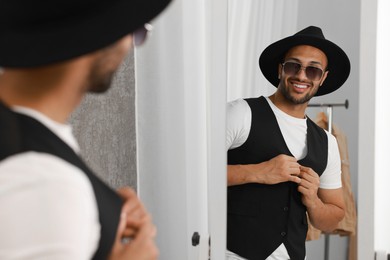 Photo of Smiling man looking at mirror at home