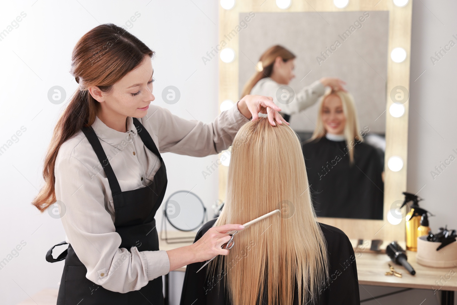 Photo of Professional hairdresser combing woman's hair in salon