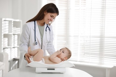 Photo of Pediatrician weighting little child in clinic. Checking baby's health