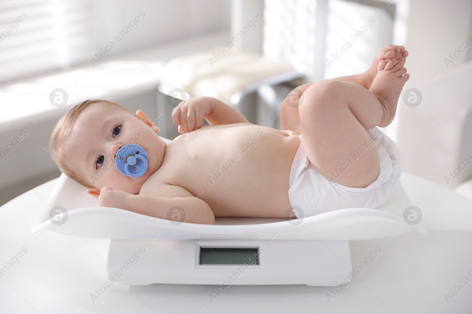 Photo of Cute little child lying on scales in clinic. Checking baby's health