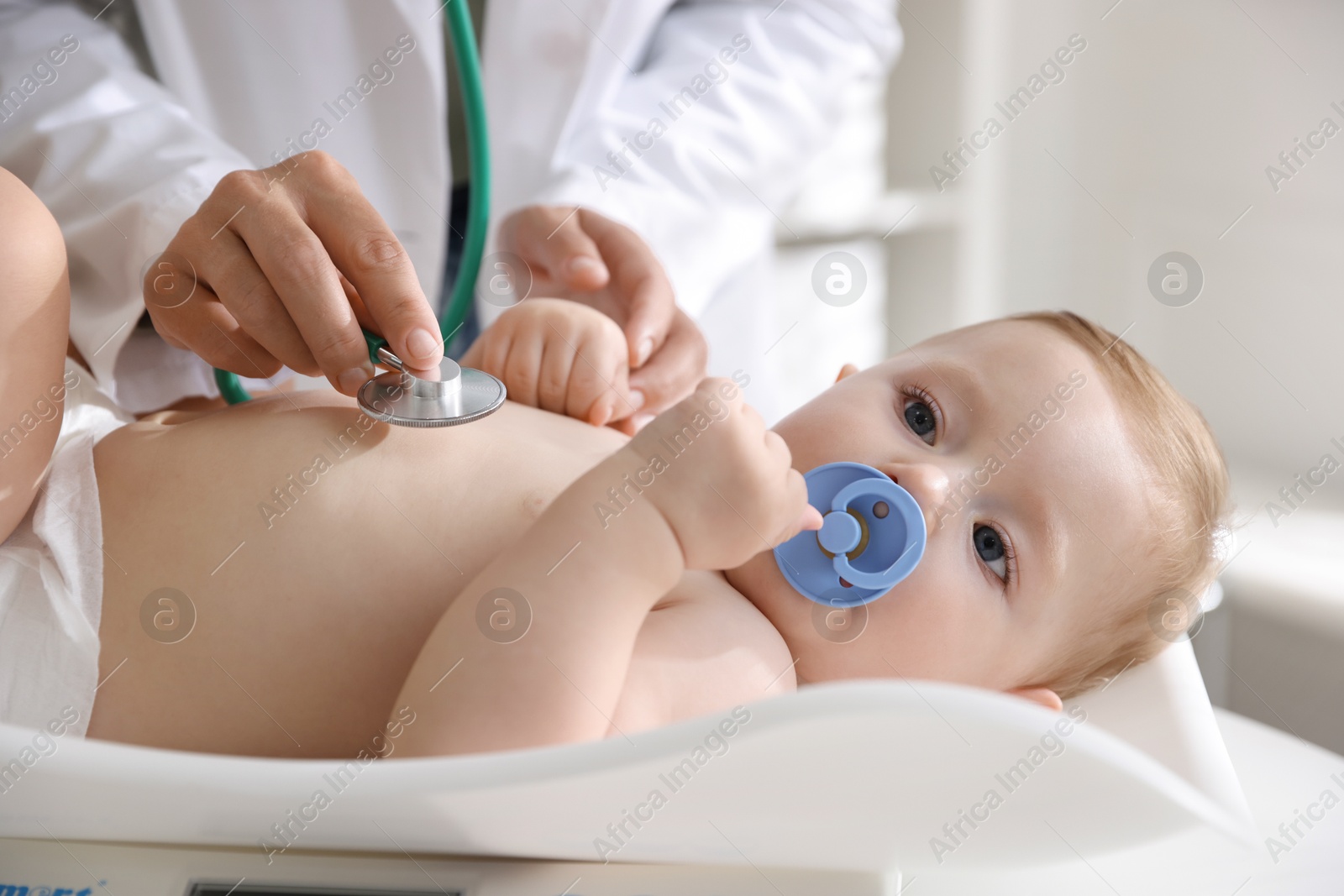 Photo of Pediatrician examining little child with stethoscope in clinic, closeup. Checking baby's health