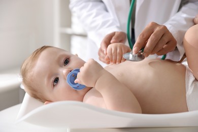 Photo of Pediatrician examining little child with stethoscope in clinic, closeup. Checking baby's health