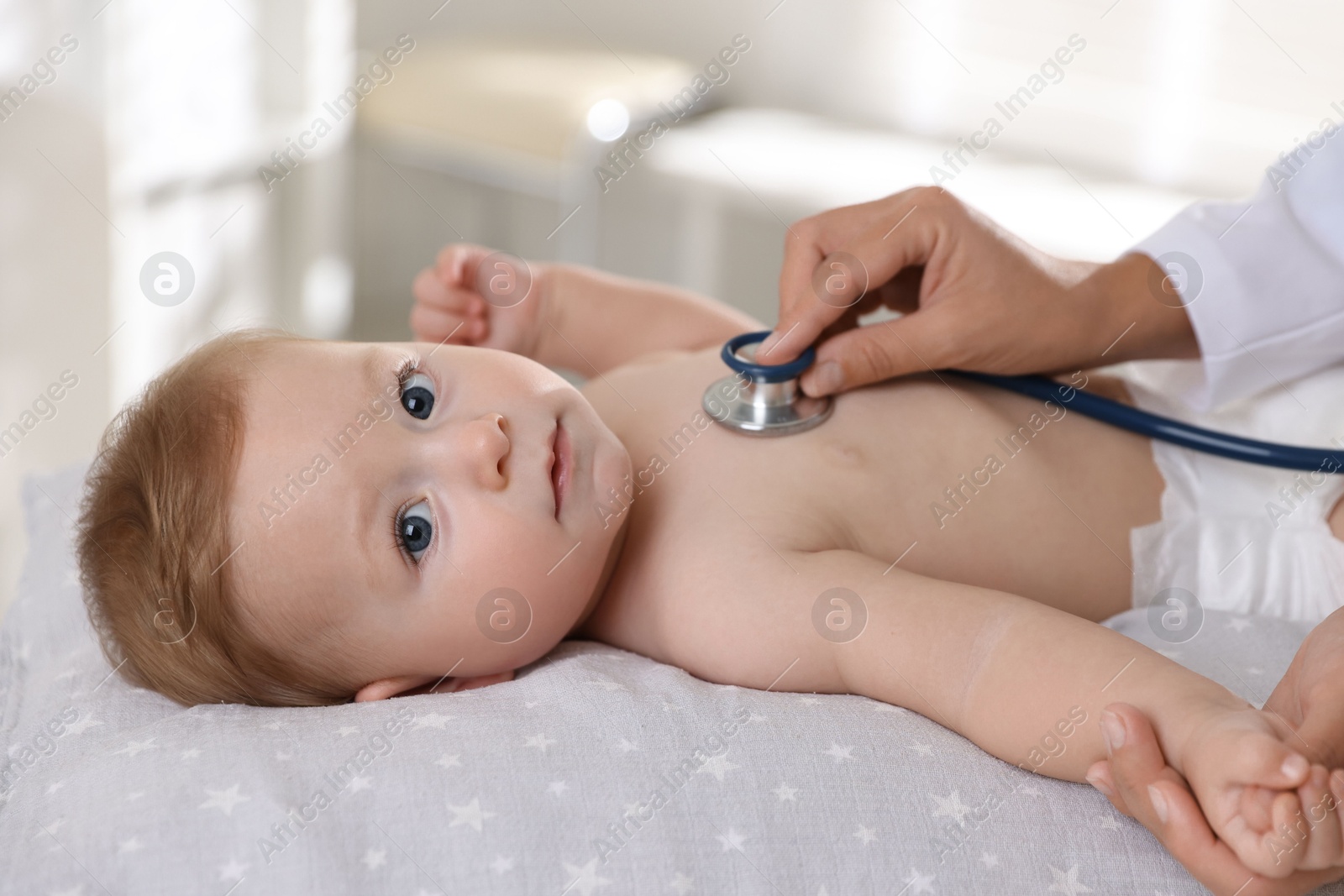 Photo of Pediatrician examining little child with stethoscope in clinic, closeup. Checking baby's health