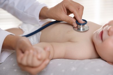 Photo of Pediatrician examining little child with stethoscope in clinic, closeup. Checking baby's health