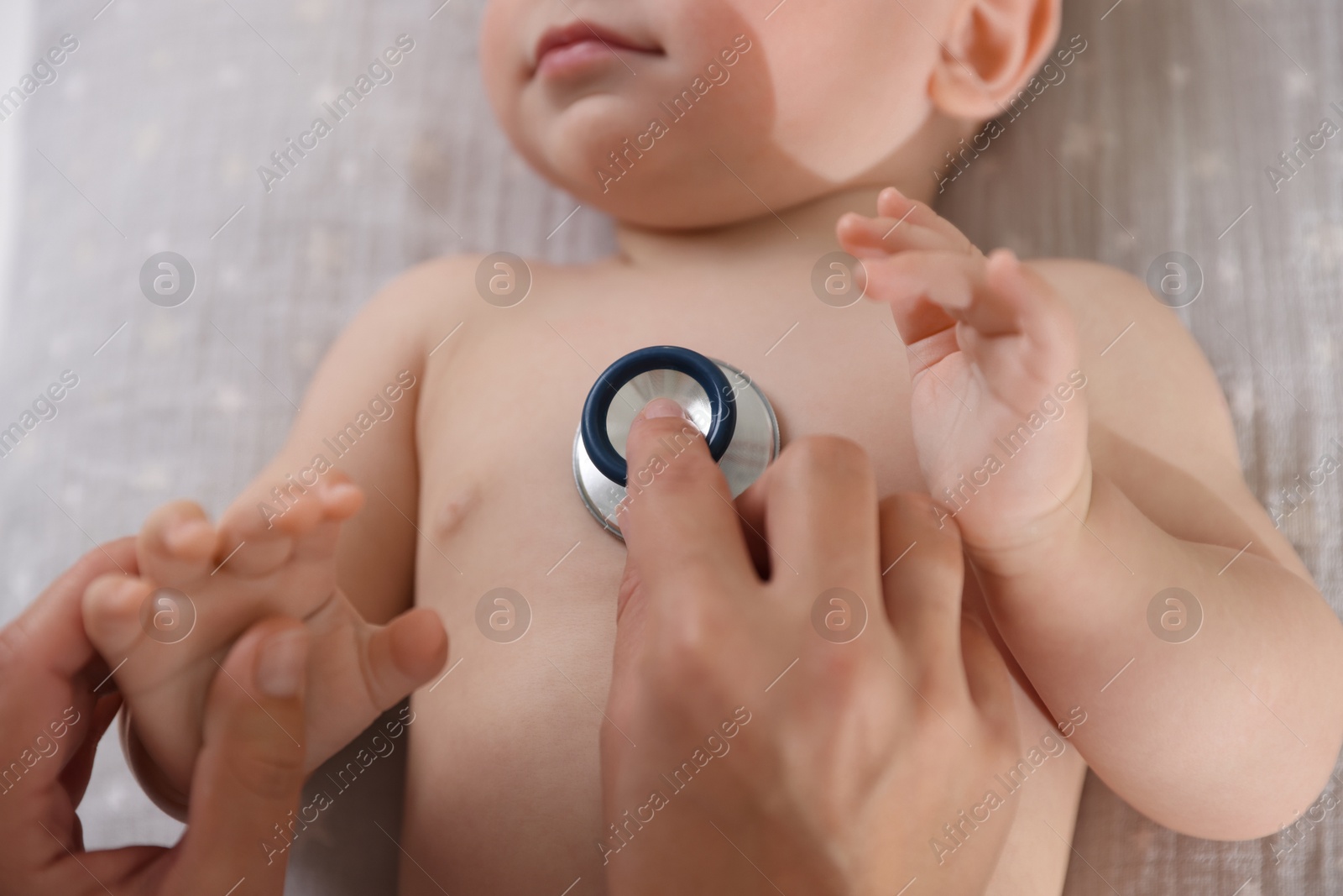 Photo of Pediatrician examining little child with stethoscope in clinic, closeup. Checking baby's health