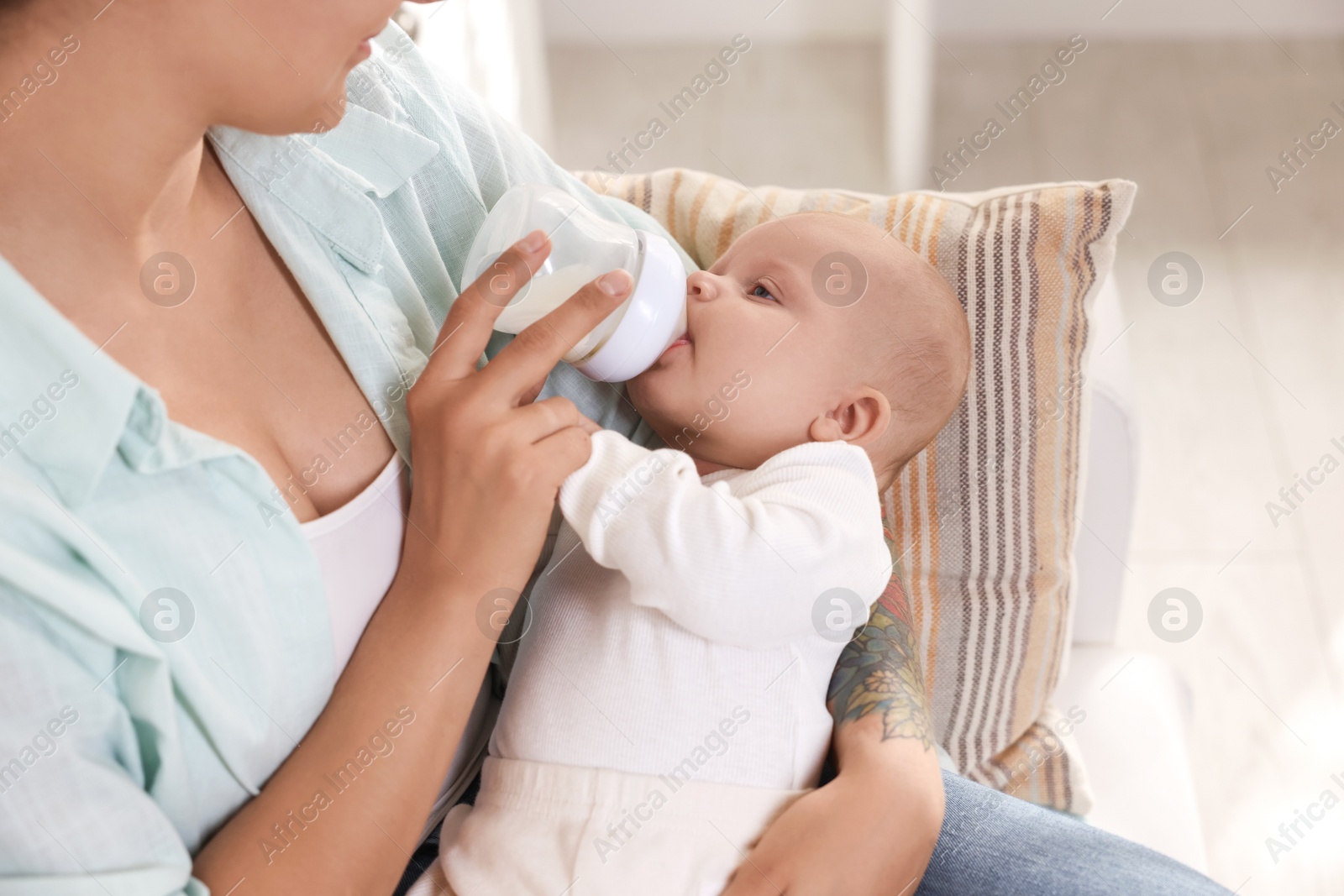 Photo of Mother feeding her cute baby indoors, closeup