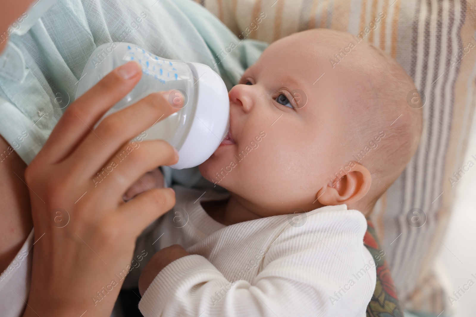 Photo of Mother feeding her cute baby indoors, closeup