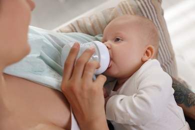 Photo of Mother feeding her cute baby indoors, closeup