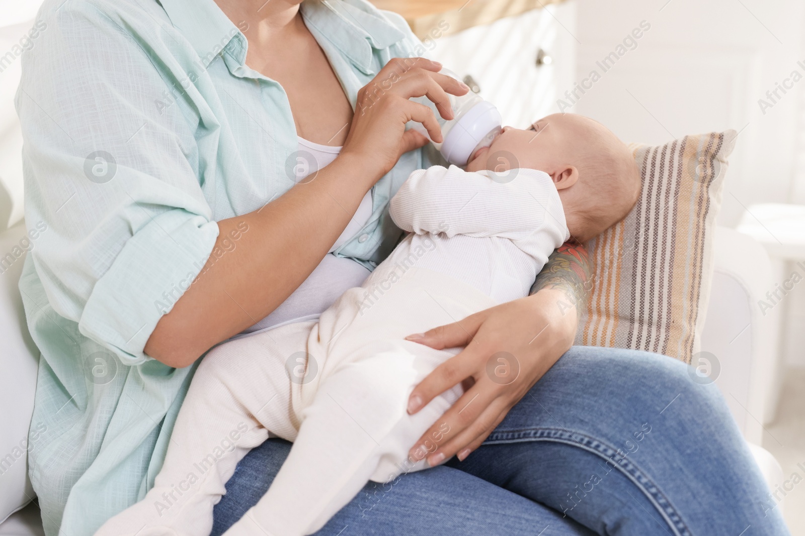 Photo of Mother feeding her cute baby indoors, closeup