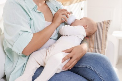 Photo of Mother feeding her cute baby indoors, closeup