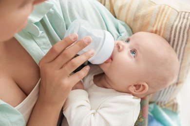 Photo of Mother feeding her cute baby indoors, closeup