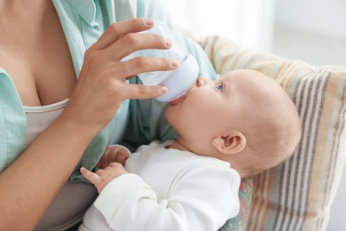 Photo of Mother feeding her cute baby indoors, closeup