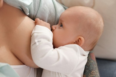 Photo of Mother breastfeeding her little baby at home, closeup