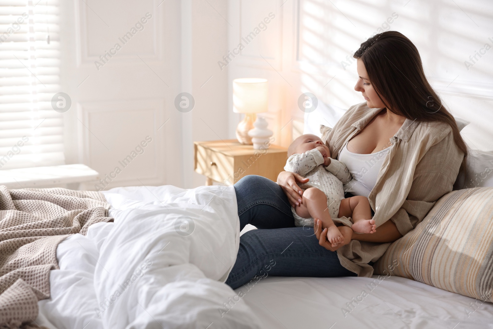 Photo of Mother with her cute little baby on bed at home