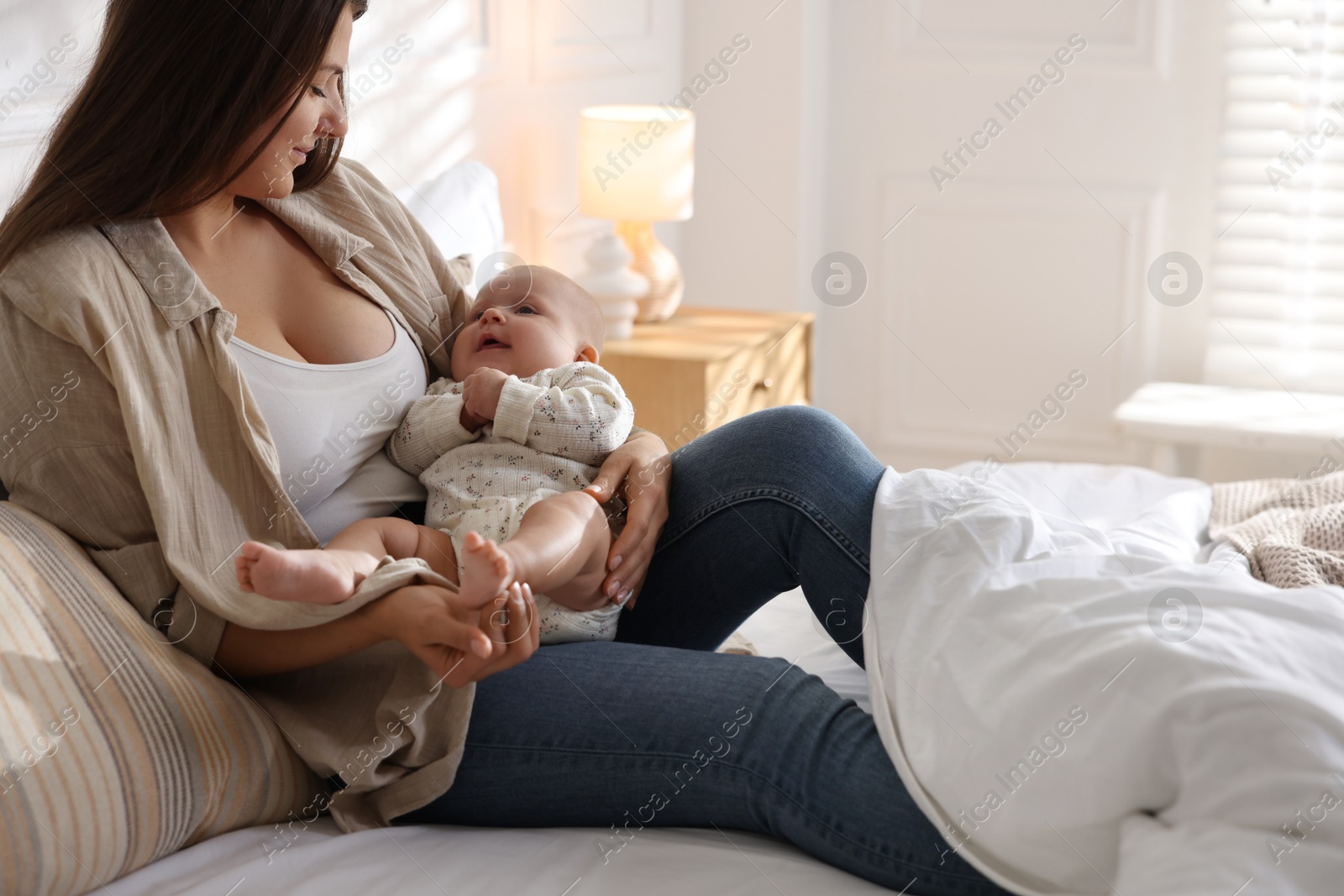 Photo of Mother with her cute little baby on bed at home