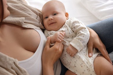 Photo of Mother with her cute little baby on bed at home, closeup