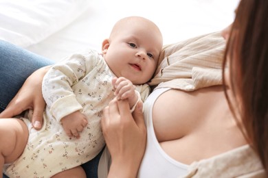 Photo of Mother with her cute little baby on bed at home, closeup