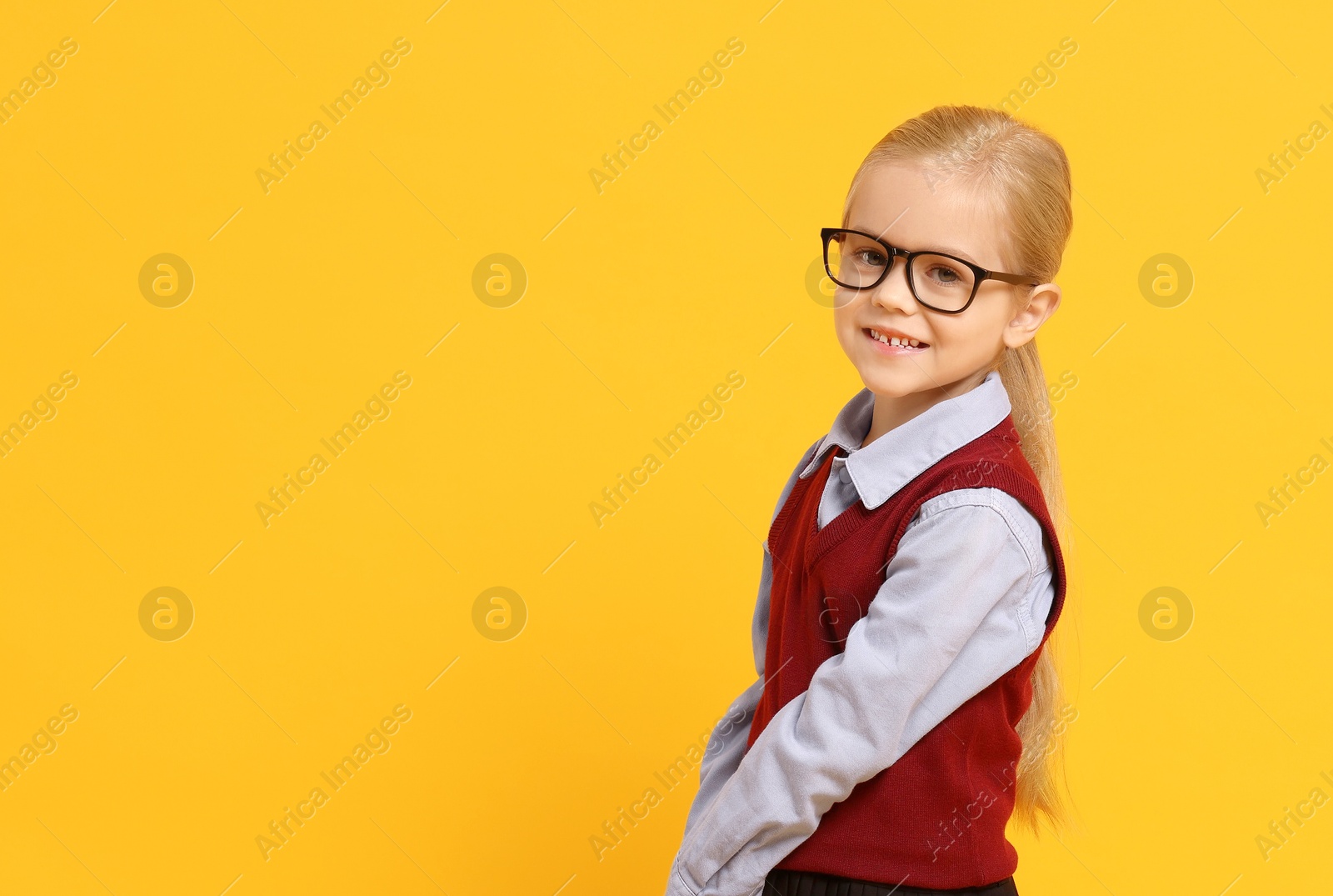 Photo of Little girl with glasses on orange background, space for text. Dreaming of future profession