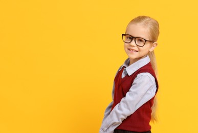 Photo of Little girl with glasses on orange background, space for text. Dreaming of future profession