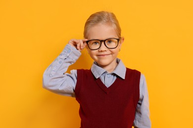 Photo of Little girl with glasses on orange background. Dreaming of future profession