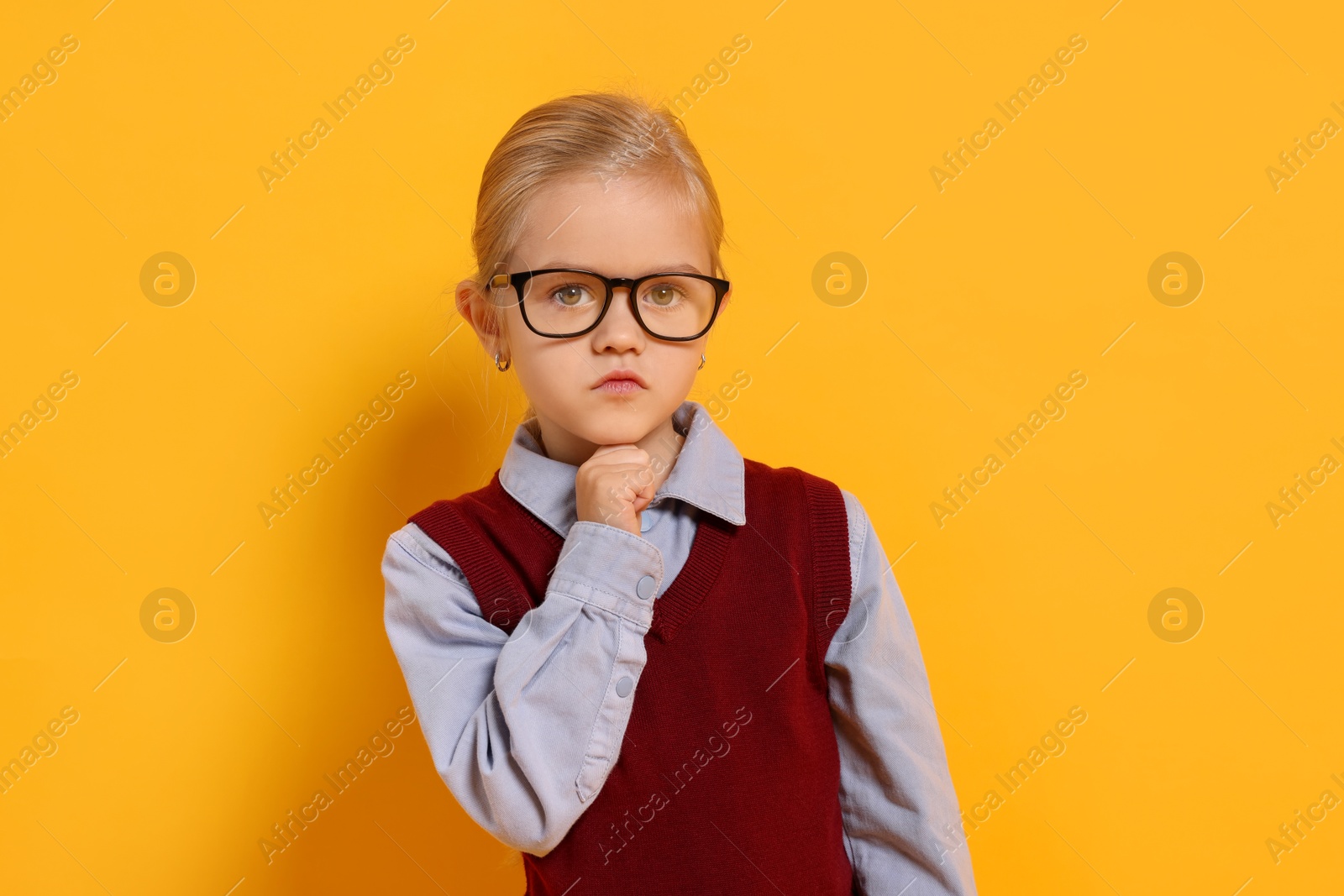 Photo of Little girl with glasses on orange background. Dreaming of future profession