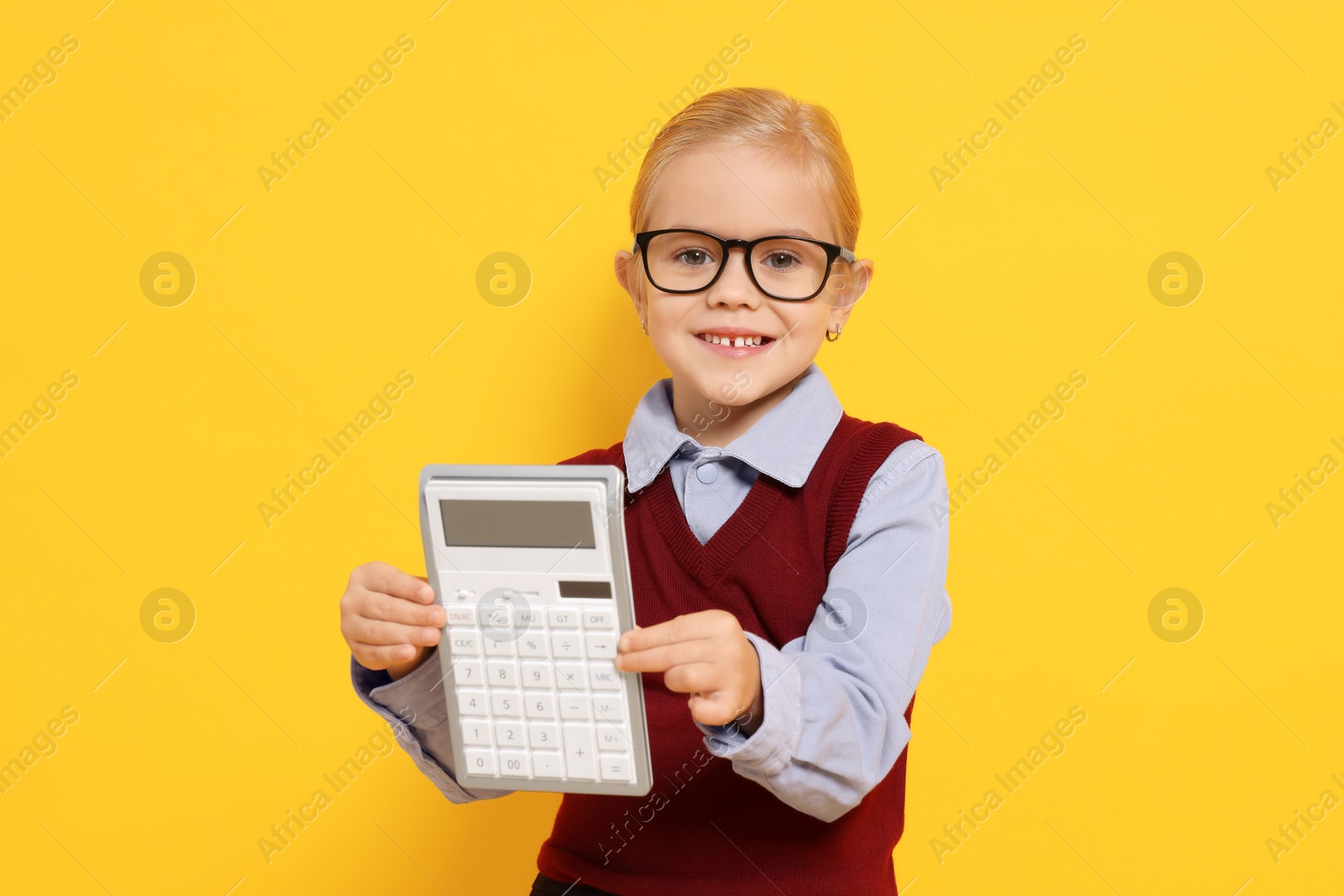 Photo of Little girl with calculator pretending to be accountant on orange background. Dreaming of future profession